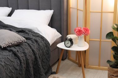 Çalar saati olan yan masa ve yatağın yanındaki dekor.