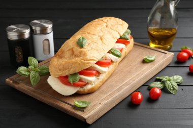 Mozarella peynirli, domatesli, fesleğenli, siyah ahşap masa, yakın plan.