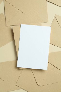 Boş davetiye kartı ve bej arka planda zarflar, düz yatış. Tasarım için boşluk