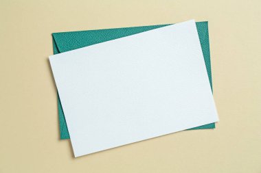 Bej arka planda boş davetiye ve zarf, üst manzara. Tasarım için boşluk