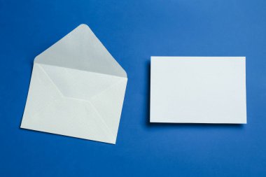 Mavi arka planda boş davetiye ve zarf var. Tasarım için boşluk