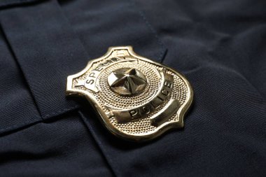 Koyu mavi üniformalı polis rozeti, yakın plan.