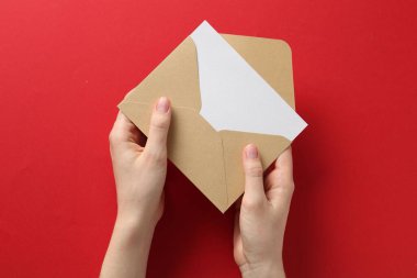 Kırmızı arkaplanda boş davetiye kartı olan kadın, üst görünüm