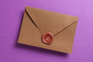 Mor arka planda balmumu mühürü olan güzel bir davetiye zarfı, üst görünüm