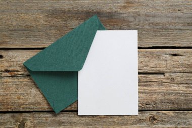 Boş davetiye kartı ve zarf ahşap masanın üstünde, üst tarafta. Tasarım için boşluk