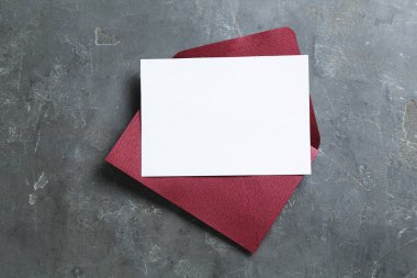 Boş davetiye kartı ve zarf gri masada, üst tarafta. Tasarım için boşluk