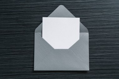 Siyah desenli masa üzerinde boş davetiye ve zarf, üst manzara. Tasarım için boşluk