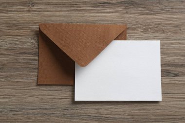 Boş davetiye kartı ve zarf ahşap masanın üstünde, üst tarafta. Tasarım için boşluk