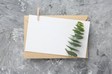 Boş davetiye kartı, gri desenli masa üzerindeki şube ve zarf, üst manzara. Metin için boşluk