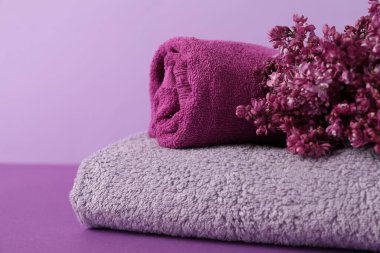 Renkli arka planda yumuşak havlular ve leylak çiçekleri, yakın plan