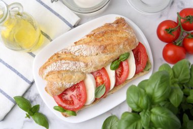 Mozarella peynirli, domatesli, fesleğenli, beyaz mermer masalı lezzetli bir sandviç.