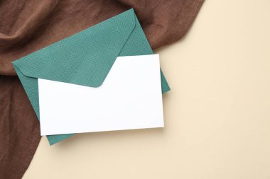 Bej arka planda boş davetiye ve zarf, üst manzara. Metin için boşluk