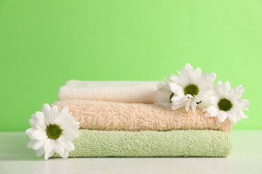 Yumuşak havlular ve yeşil arka planda kasımpatı çiçekleri, yakın plan.