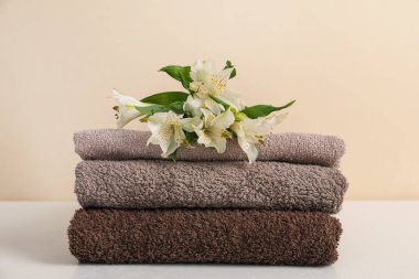 Beyaz masa üzerinde bej arka planda yumuşak havlu ve zambak yığını, yakın plan