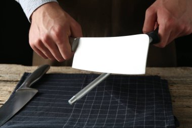 Ahşap masada bileyiciyle bileyen adam, yakın plan.