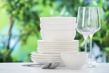 Bulanık yeşil arka planda beyaz masada farklı temiz tabaklar