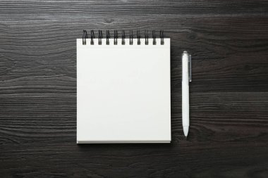 Boş defter ve kalemi siyah ahşap masa üzerinde aç, üst görünüm