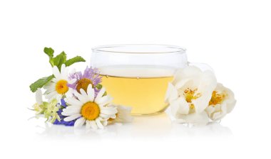 Cam bardakta aromatik bitki çayı ve beyaz bardakta izole edilmiş çiçekler.