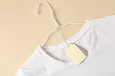 Bej arkaplan etiketli beyaz tişört, üst görünüm