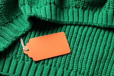 Yeşil örülmüş süveterin üzerindeki karton etiket, yukarıda.