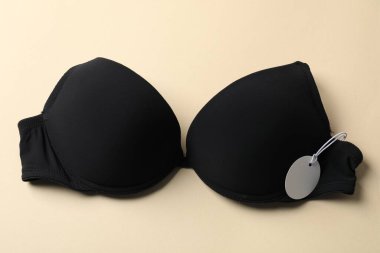 Bej arka planda etiketli siyah sutyen, üst görünüm