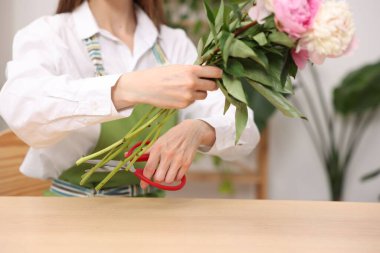 Çiçekçinin ahşap masasında şakayık buketi yapan çiçekçi, yakın plan.