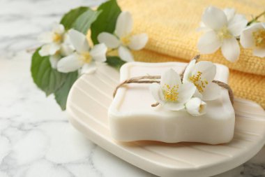 Sabun çubuğu ve yasemin çiçekleri beyaz mermer masada, yakın plan.