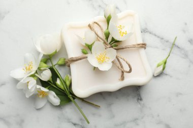 Sabun çubuğu ve yasemin çiçekleri beyaz mermer masada, düz yatıyordu.