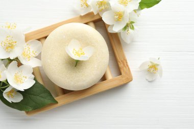 Sabun çubuğu ve yasemin çiçekleri beyaz ahşap masada, düz yerde. Metin için boşluk