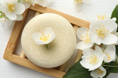 Sabun çubuğu ve yasemin çiçekleri beyaz ahşap masada, düz yatıyordu.