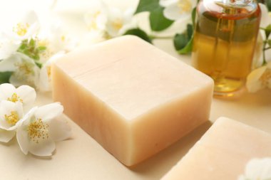 Sabun çubukları, esaslı yağ ve yasemin çiçekleri bej arka planda, yakın plan