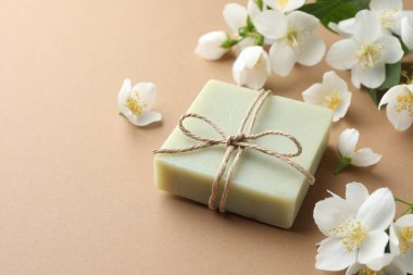 Açık kahverengi arka planda sabun ve yasemin çiçekleri, yakın plan. Metin için boşluk