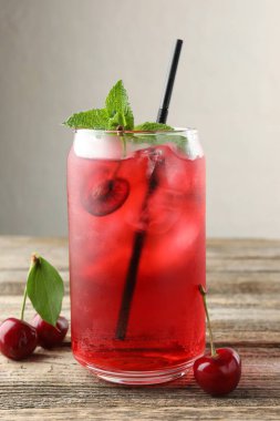 Buzlu vişneli gazoz, böğürtlen ve nane şekeri ahşap masada, yakın plan.