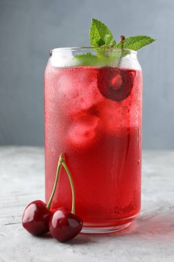 Buzlu vişneli gazoz, böğürtlen ve nane. Gri desenli masa, yakın plan.