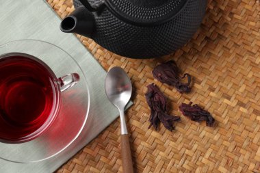 Cam fincanda leziz amber çayı, çaydanlık, kuru roselle sepals ve hasır üzerinde kaşık, düz uzanma