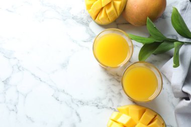 Lezzetli mango suyu bardakta, taze meyve ve beyaz mermer masada yapraklar, düz yatak. Metin için boşluk