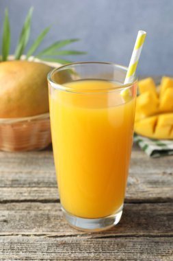 Bardakta lezzetli mango suyu ve ahşap masada taze meyve, yakın plan.