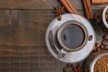 Bir fincan aromatik kahve, fasulye, hazır toz ve ahşap masa üzerindeki baharatlar, düz yatak. Metin için boşluk