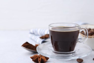 Bir fincan aromatik kahve, fasulye ve yıldız anason beyaz masada, yakın plan. Metin için boşluk