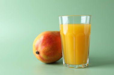 Bardakta lezzetli mango suyu ve yeşil arka planda taze meyve.