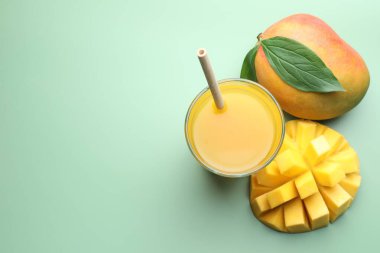 Lezzetli mango suyu bardakta ve yeşil arka planda taze meyveler düz yerde. Metin için boşluk