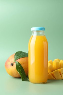 Cam şişede lezzetli mango suyu ve yeşil arka planda taze meyve.