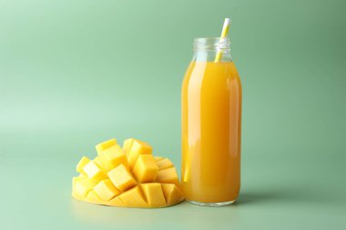 Cam şişede lezzetli mango suyu ve yeşil arka planda taze meyve.