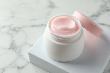 Beyaz mermer masanın üzerinde bir kavanoz nemlendirici vücut kremi, yakın plan. Metin için boşluk