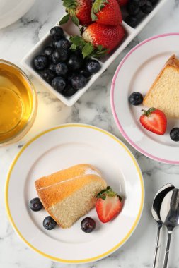 Böğürtlenli kek parçaları ve beyaz mermer masa üzerinde çay, düz yatıyordu