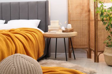 Yatağın yanında kitap ve dekor olan yan masa.