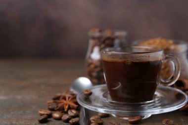 Bir fincan aromatik kahve, fasulye, hazır toz ve baharatlar ahşap masada, yakın plan. Metin için boşluk