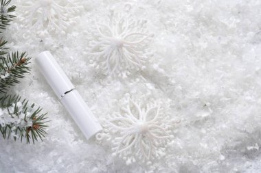 Nemlendirici dudak kremi, Noel dekorasyonu ve yapay kar üzerinde köknar ağacı dalları. Metin için boşluk