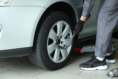 Tamirci araba servisinde lastik değiştiriyor, yakın plan.