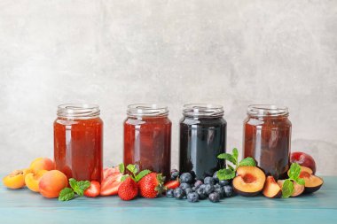 Kavanozlardaki farklı reçeller ve mavi ahşap masadaki malzemeler. Metin için boşluk